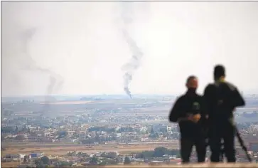  ?? Lefteris Pitarakis Associated Press ?? SMOKE from a fire in Ras al-Ayn in Syria serves as a backdrop for TV journalist­s in Ceylanpina­r, Turkey.