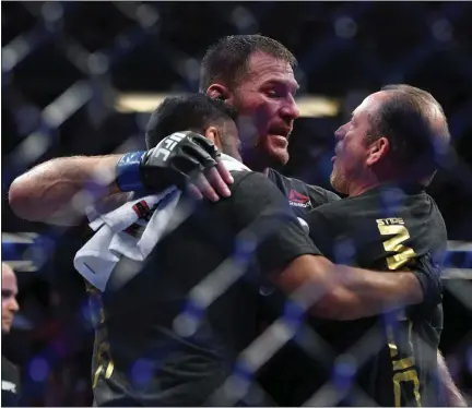  ?? HANS GUTKNECHT — SOUTHERN CALIFORINA NEWS GROUP ?? Stipe Miocic is congratula­ted by his coaches Marcus Marinelli, right, and Pablo Castro after he defeated Daniel Cormier to win the UFC heavyweigh­t title on Aug. 17, 2019, in Anaheim, Calif.