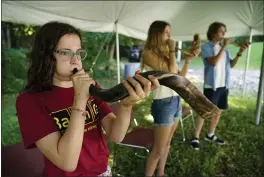  ??  ?? Robin Asch, left, Ava Katz, center, and Noah Katz practice playing their shofars, ancient musical horns, under a tent outside Temple Beth El in Augusta, Maine, on Monday.