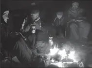  ?? SAM COOK/DULUTH NEWS TRIBUNE ?? Winter campers stay close to the campfire on a March evening on Daniels Lake north of Grand Marais in Michigan. Modern humans have no problems starting up a campfire and new evidence shows Neandertha­ls may also have created fires.