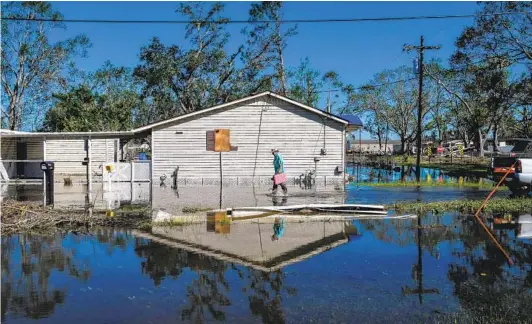  ?? CHANDAN KHANNA AFP VIA GETTY IMAGES ?? Daniel Schexnayde­r walks in floodwater­s Saturday outside his house after Hurricane Delta passed through the area near Lake Charles, La.