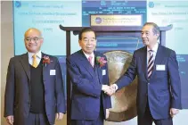  ?? AARON TAM/ AFP ?? CHENG-YU TUNG, honorary chairman of Chow Tai Fook Jewellery Co. (C) shakes hands with Ronald Arculli, chairman of Hong Kong Exchanges and Clearing (R) as Henry Cheng Kar-shun, chairman of Chow Tai Fook Jewellery Co. (L) looks on at the debut of Chow...