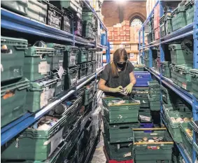  ??  ?? A volunteer makes up parcels for vulnerable families at a food bank.