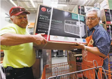  ?? Elaine Thompson / Associated Press ?? Store greeter Danny Olivar (right) helps a customer with an air conditione­r at a Home Depot in Seattle.
