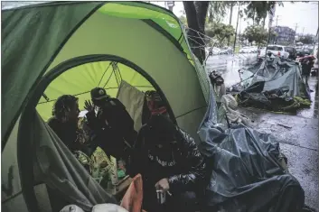  ?? DAMIAN DOVARGANES/AP ?? IN THIS MARCH 12, 2020, FILE PHOTO, people try to stay warm as they face the elements inside a homeless encampment flooded under a rainstorm across the Echo Park Lake in Los Angeles.