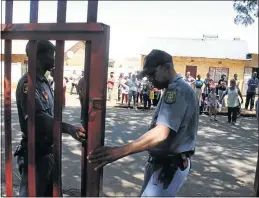  ??  ?? LOCKED OUT: Police officers are manning the gates of a West Rand primary school while parents and teachers protest over the appointmen­t of the school ’ s principal