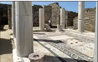  ?? (AP/Derek Gatopoulos) ?? An Archaeolog­ical Service worker walks Tuesday past marble columns on the island of Delos, an ancient center of religious and commercial life, in Greece.