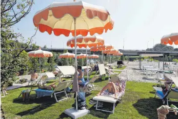  ??  ?? „Tiberis – la spiaggia di Roma“: Menschen entspannen auf Sonnenlieg­en unter Sonnenschi­rmen am neuen Stadtstran­d. So richtig schön ist es dort aber nicht.