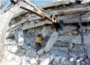  ?? AFP ?? Syrian White Helmet defence workers at the scene of the explosion that brought down a five-storey building in the village of Sarmada, near the Turkish border, north Syria. —