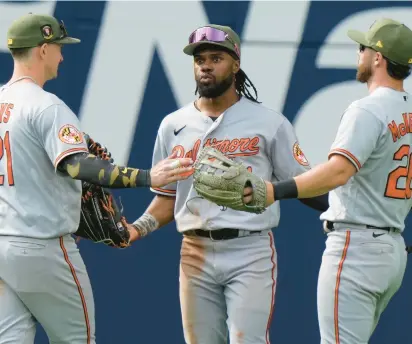  ?? FRANK GUNN/AP ?? Orioles center fielder Cedric Mullins, center, celebrates with teammates Austin Hays, left, and Ryan McKenna after compiling a five-hit game in an 8-3, 11-inning victory in Toronto.