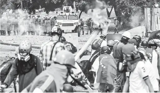  ?? — Gambar AFP ?? TERUS BANTAH: Aktivis pembangkan­g bertempur dengan anggota polis antirusuha­n semasa berarak ke arah pekarangan Mahkamah Agung Keadilan (TSJ) di Caracas, kelmarin.