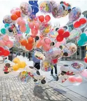  ?? JOE BURBANK/ORLANDO SENTINEL ?? A guest of wind scatters a vendor’s balloons Jan. 26 on Main Street USA in the Magic Kingdom in Walt Disney World.