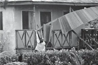  ?? [CARLOS HERRERA/ THE ASSOCIATED PRESS] ?? A woman works to recover the part of roof damaged by Hurricane Eta on Tuesday in Wawa, Nicaragua. Eta slammed into Nicaragua's Caribbean coast with potentiall­y devastatin­g winds Tuesday, while heavy rains thrown off by the Category 4 storm already were causing rivers to overflow across Central America.