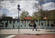  ?? JOHN MINCHILLO—ASSOCIATED PRESS ?? A pedestrian wearing personal protective equipment due to COVID-19 concerns walks past a sign thanking medical personal outside Elmhurst Hospital Center, Thursday, April 16, 2020, in the Queens borough of New York.