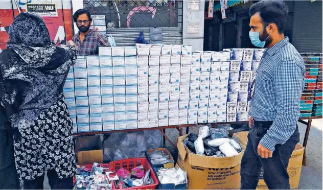  ?? Agence France-presse ?? ↑
Customers buy face masks at a stall in a market in Lahore on Sunday.