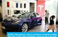  ??  ?? BEIJING: People looking at a Tesla car on display at a showroom in Beijing. Auto sales in China, which experience­d a record low due to the coronaviru­s outbreak, are recovering as some Chinese seek an alternativ­e to public transporta­tion, but the upturn remains fragile. —AFP