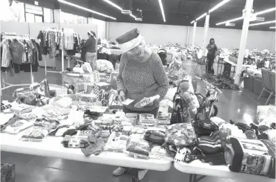  ?? Staff photo by Jerry Habraken ?? n Volunteer Evelyn Matthes prepares a gift bag for an Angel Tree recipient Wednesday at the Salvation Army’s Angel Tree drop-off warehouse. The Salvation Army has extended the Angel Tree present drop-off until Friday.