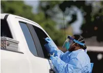  ?? KAITLIN MCKEOWN/STAFF ?? A healthcare worker administer­s a coronaviru­s test during a drive-thru COVID-19 testing event on Tuesday at the Suffolk Health Department.