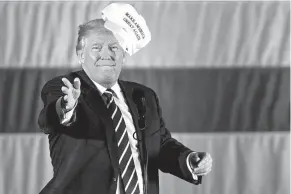  ?? Associated Press ?? President-elect Donald Trump throws a hat into the audience Friday while speaking at a rally in a DOW Chemical Hanger at Baton Rouge Metropolit­an Airport in Baton Rouge, La.