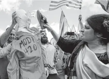  ?? Godofredo A. Vásquez / Staff photograph­er ?? A woman uses her shoe to hit a dummy with a cutout face of Modi, wearing a prison jumpsuit during a protest Sunday outside NRG Stadium. Organizers estimate the protest crowd between 12,000 and 15,000.