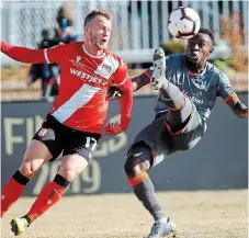  ?? JEFF MCINTOSH THE CANADIAN PRESS FILE PHOTO ?? Hamilton Forge’s Kwame Awuah, right, kicks the ball as Calgary Cavalry’s Nico Pasquotti looks on during last November’s Canadian Premier League soccer finals.