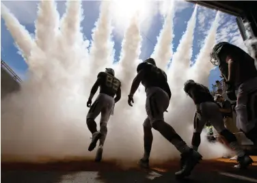  ?? Associated Press ?? ■ Baylor defensive tackle Micheal Johnson, left, leads teammates onto the field Sept. 10 before an NCAA college football game against SMU in Waco, Texas. Defensive-minded West Virginia and Baylor will try this week to remain the Big 12's only...