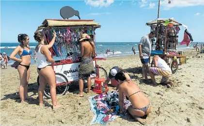  ??  ?? Compradore­s. La imagen se repite en cada playa: clientes que buscan calzados y atuendos de verano.
