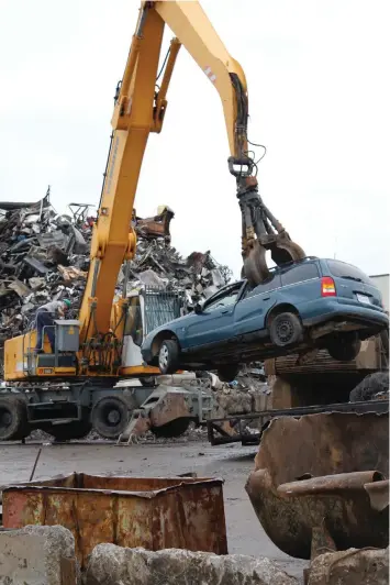  ?? Staff photo by Junius Stone ?? A grappler lifts a car off of a trailer Wednesday to place it in front of a machine that will shred it into its component materials at Tri-State Iron and Metal Salvage Yard in Texarkana, Ark.