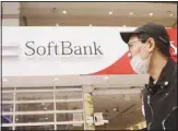  ?? In this file photo, people walk by a SoftBank shop in Tokyo. (AP) ??