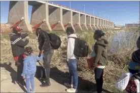  ?? AP file photo ?? A Mexican smuggler guides a Haitian family across the Morelos Dam over the Colorado River from Los Algodones, Mexico, on Feb. 4, to Yuma, Ariz., on the other side. The Biden administra­tion released a plan Tuesday to deal with an increase in already historic numbers of migrants at the U.S.-Mexico border with the lifting of a public health order that has kept people from seeking asylum — and that Republican and some Democratic lawmakers say should be kept in place.