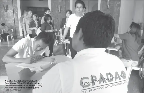  ?? MITZI A. AMBRAD ?? A staff of the Cebu Provincial AntiDrug Abuse Office (CPADAO) guides a Capitol employee as he fills out a drug test form while others wait in queue.