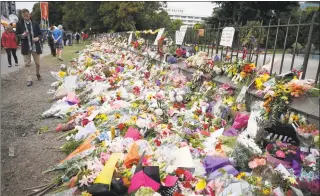  ?? Vincent Thian / Associated Press ?? Mourners lay flowers on a wall at the Botanical Gardens in Christchur­ch, New Zealand, on Monday. A steady stream of mourners paid tribute at makeshift memorial to the 50 people slain by a gunman at two mosques in Christchur­ch, while dozens of Muslims stood by to bury the dead when authoritie­s finally release the victims' bodies.