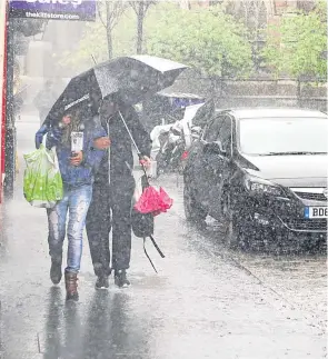  ??  ?? Locals taking shelter during a torrential downpour in the city last month.