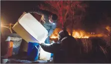  ?? HERALD PHOTO TIJANA MARTIN ?? Sam Schofield helps distribute water among local volunteers as they try to put out hot spots on a property after a fire broke out in Moon River Estates, west of Lethbridge on Tuesday.