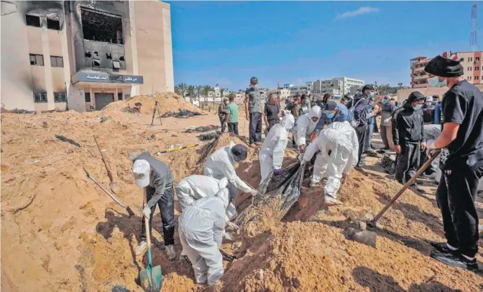  ?? AFP ?? Trabajador­es de la salud palestinos desentierr­an un cuerpo en el complejo hospitalar­io Al Naser, en Jan Yunis, al sur de la franja de Gaza, mientras continúan las batallas entre Hamas y las fuerzas israelíes.