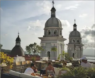  ??  ?? Patrons enjoy drinks on the rooftop bar of the Hotel Casa Granda in Santiago de Cuba.