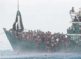  ??  ?? TROUBLED WATERS: Rohingya migrants jump to collect food supplies dropped by a Thai army helicopter from a boat in Thai waters off the southern island of Koh Lipe in the Andaman Sea.
