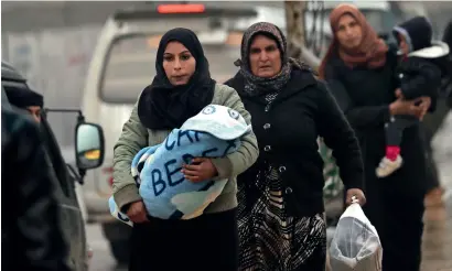  ?? — AFP ?? Syrian women carry children in the northern town of Manbij on Turkish border on Sunday.