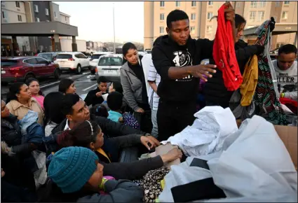  ?? ?? Jeison Hurtado Pulgarin, right, from Colombia, hands out donated clothes to Venezuelan migrants in the parking lot of a hotel in Denver on Feb. 5. Hurtado Pulgarin came to the U.S. two months ago but feels the need to help new arrivals in any way he can.