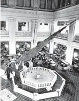  ?? CHICAGO TRIBUNE HISTORICAL PHOTO ?? Workmen install a giant 45 foot-tall Christmas tree in Marshall Field’sWalnut Room on Nov. 20, 1959, in the State Street store in Chicago.