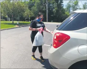  ?? ZACHARY SRNIS - THE MORNING JOURNAL ?? Katie Krueger, a shelter advocate at Genesis House and a former intern at Oberlin Community Services, places a bag of school supplies in a trunk during the drive-thru distributi­on.