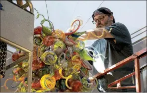  ?? Arts & Science Center for Southeast Arkansas ?? Pine Bluff artist James Hayes installs his blown-glass Celebratio­n Chandelier in the rotunda of the Arts &amp; Science Center for Southeast Arkansas in October.