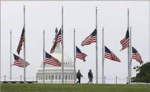  ?? AP PHOTO/PATRICK SEMANSKY ?? People walk past American flags flying at half-staff at the Washington Monument in Washington. President Donald Trump ordered American flags to be flown at half-staff for a three-day period in remembranc­e of Americans who have lost their lives due to the coronaviru­s outbreak.