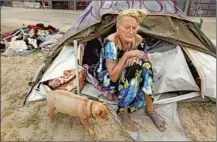  ??  ?? TERESA ROBLES and her dog, Notcho, live along the boardwalk in an area where a sheriff’s official says he counted 47 tents.