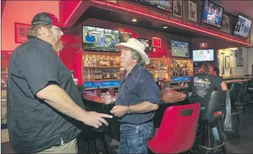  ?? Hayne Palmour IV San Diego Union-Tribune ?? D E M O C R AT Pete Beauregard, center, with Larry Miller at the Turkey Inn in Ramona, says that some voters in town believe GOP Rep. Duncan Hunter is being persecuted but others are starting to turn against him.