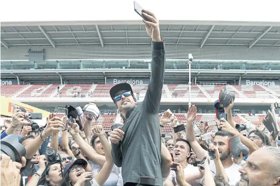  ??  ?? McLaren driver Fernando Alonso takes a selfie with fans in Barcelona.