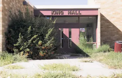  ?? JASON STILGEBOUE­R/FOR THE NEW MEXICAN ?? Weeds have overgrown the front entrance of the King Hall dormitory at the Santa Fe University of Art and Design. As the school nears its closure date, more buildings are shuttered.