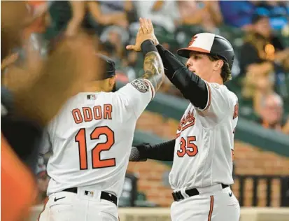  ?? TERRANCE WILLIAMS/AP ?? Orioles catcher Adley Rutschman, right, high-fives second baseman Rougned Odor, left, after scoring on Ryan Mountcastl­e’s single in the third inning Tuesday against the Toronto Blue Jays in Baltimore.