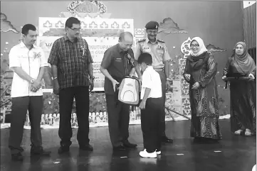  ??  ?? Masir (third left) presenting school bags to a recipient, witnessed by Ismawie (second left).