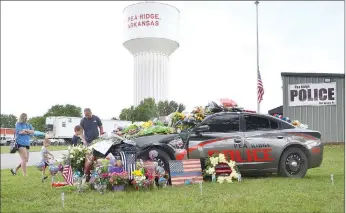  ?? TIMES photograph by Annette Beard ?? Community members lay flowers, placed artwork, placed pinwheels on and around the Pea Ridge Police patrol vehicle assigned to Officer Kevin Apple, who was killed in the line of duty Saturday, June 26.